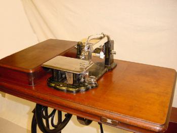 Die Nähmaschine hat eine gebogene Nadel. Baujahr 1864